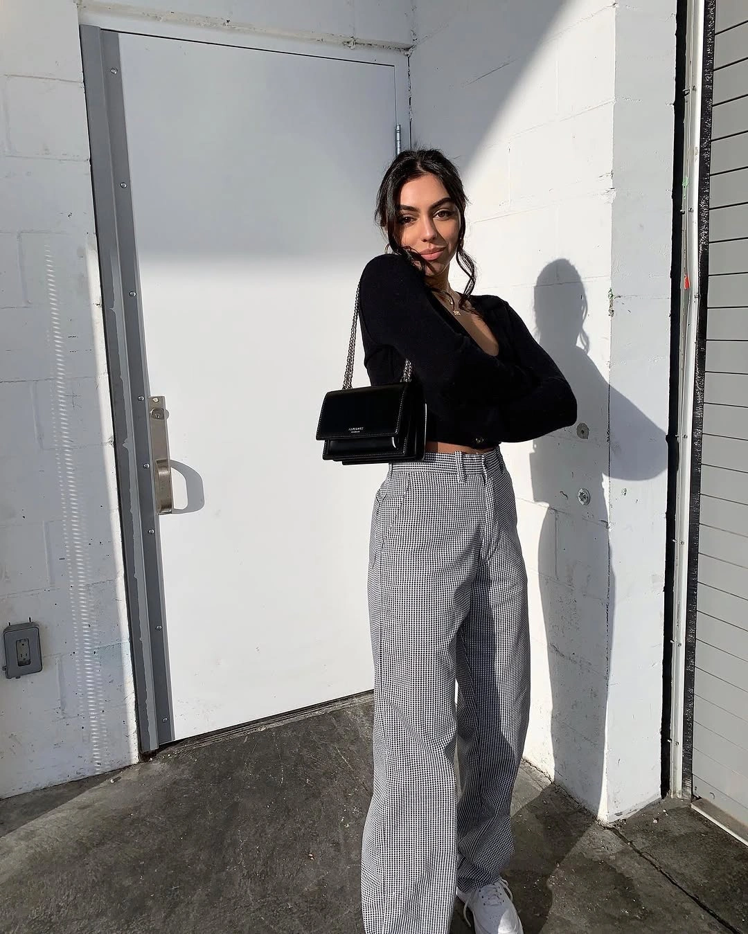 Black cropped long-sleeve top with high-waisted gray trousers and shoulder bag