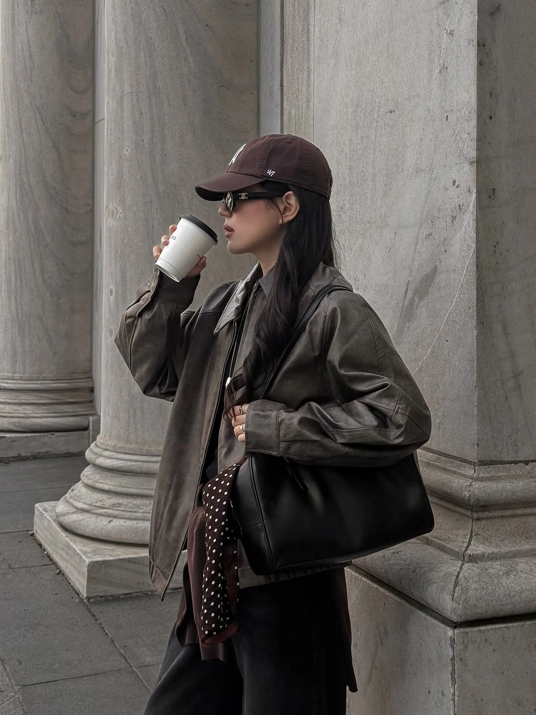 Olive-brown oversized jacket, brown cap, black bag, and spotted fabric accent