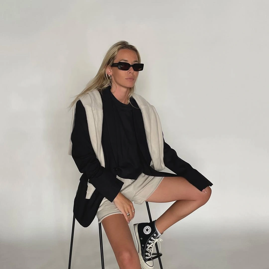Black oversized blazer, pale shoulder layer, light shorts, and high-top sneakers