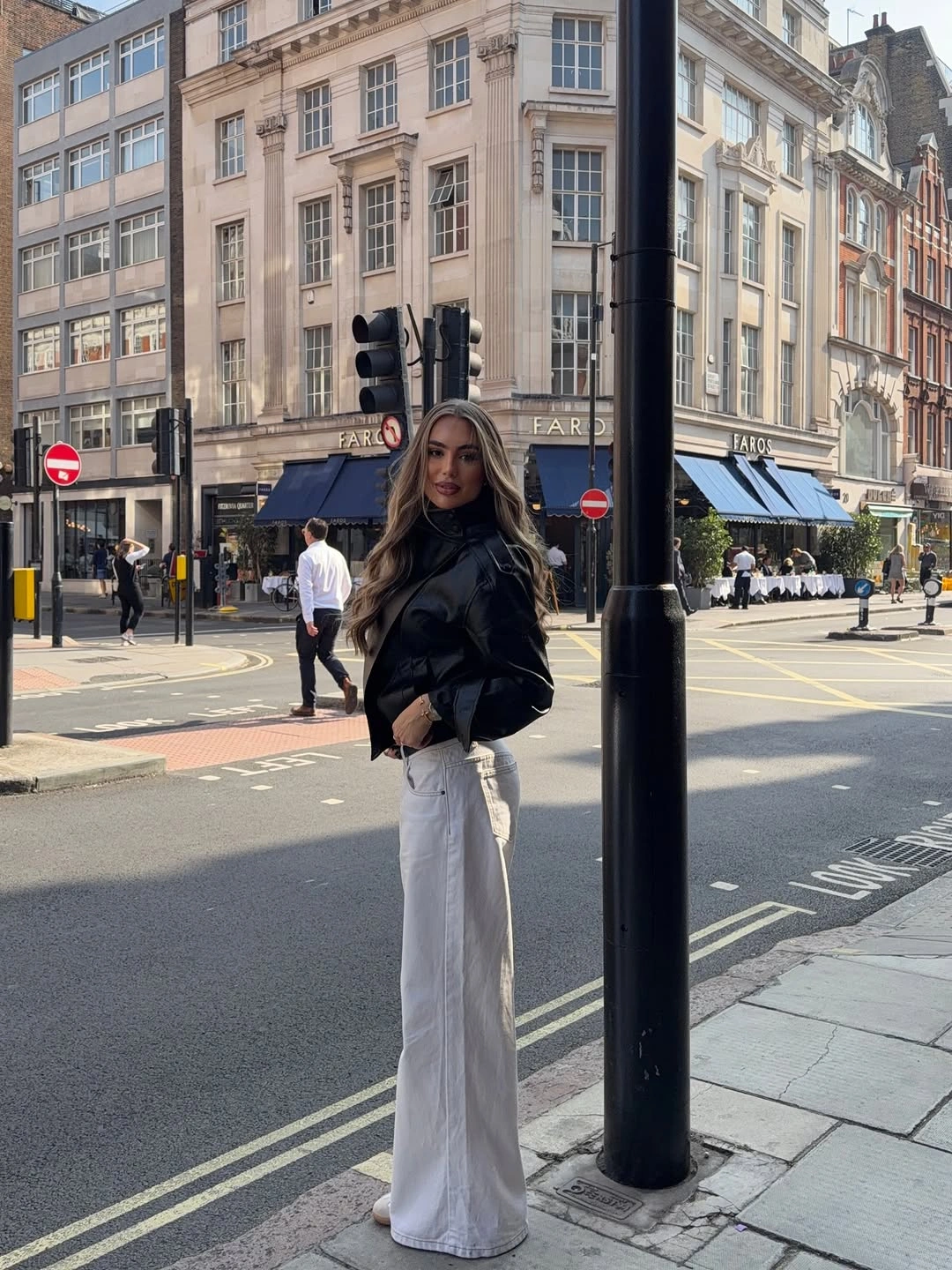 Short black jacket, wide pale trousers, and light-colored footwear