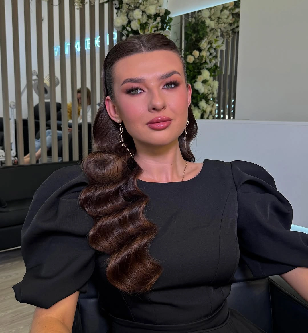 Center-parted dark hair with waves over one shoulder