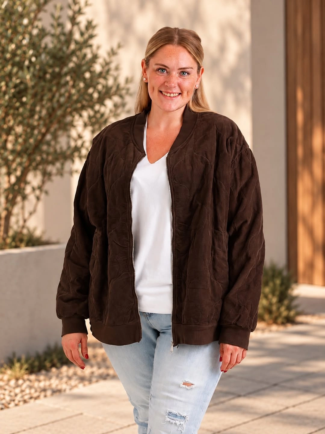 Dark brown loose bomber jacket white V-neck top and light distressed jeans