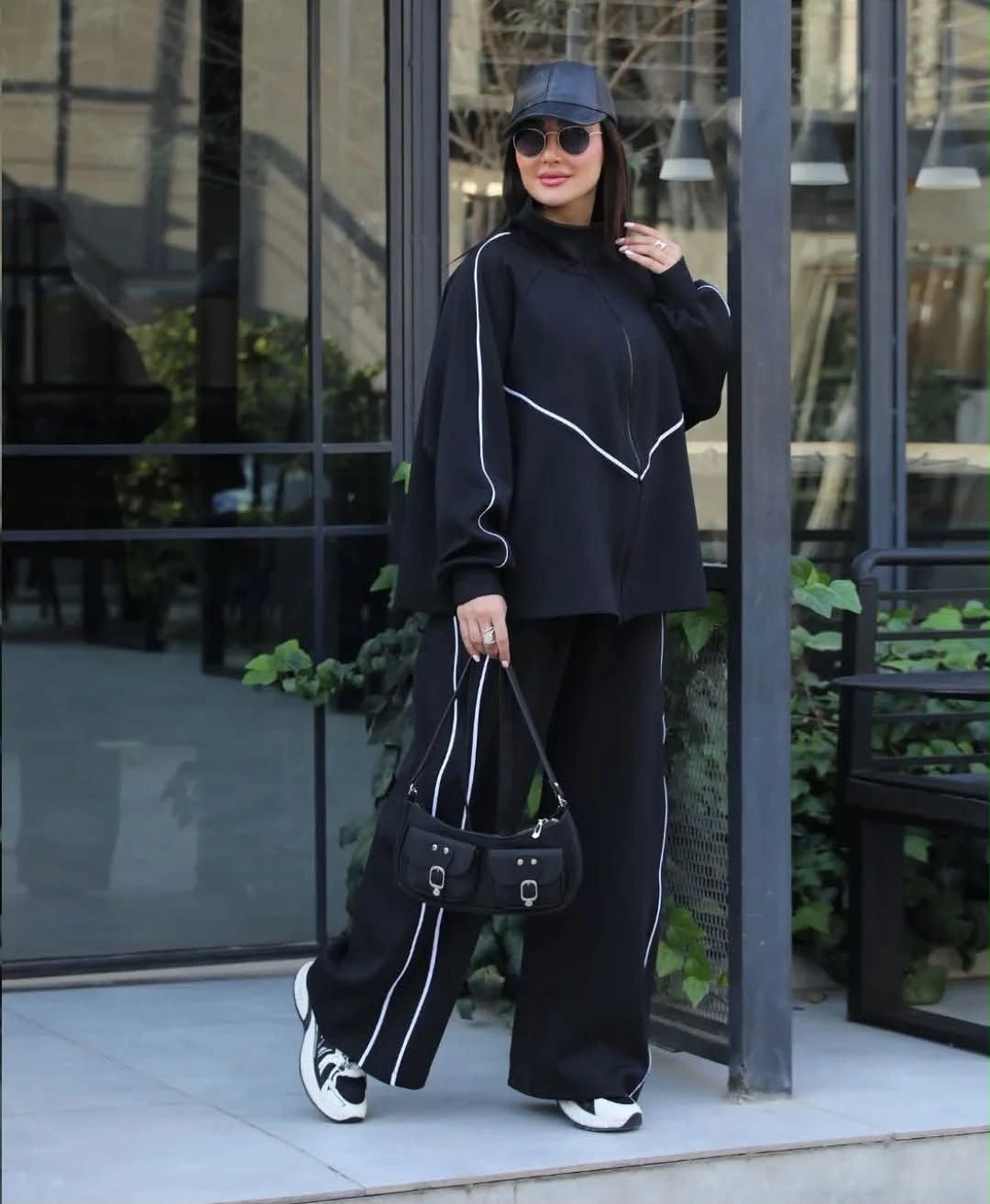 Oversized black high-neck top and wide trousers with white piping and sneakers