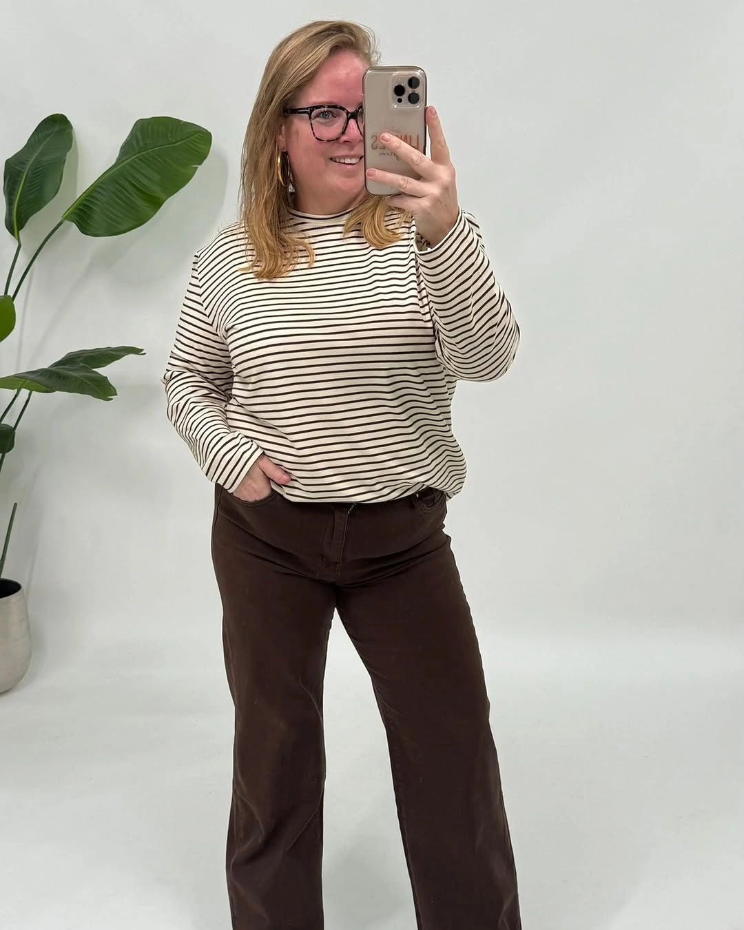 Cream long-sleeved striped top with chocolate wide-leg trousers dark belt and glasses