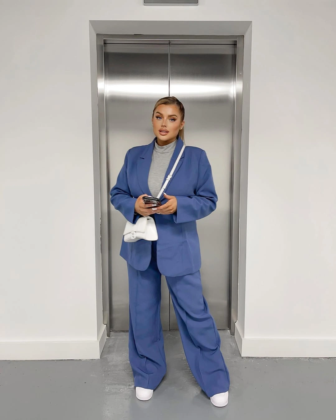 Oversized blue blazer and wide trousers with gray top and white accessories