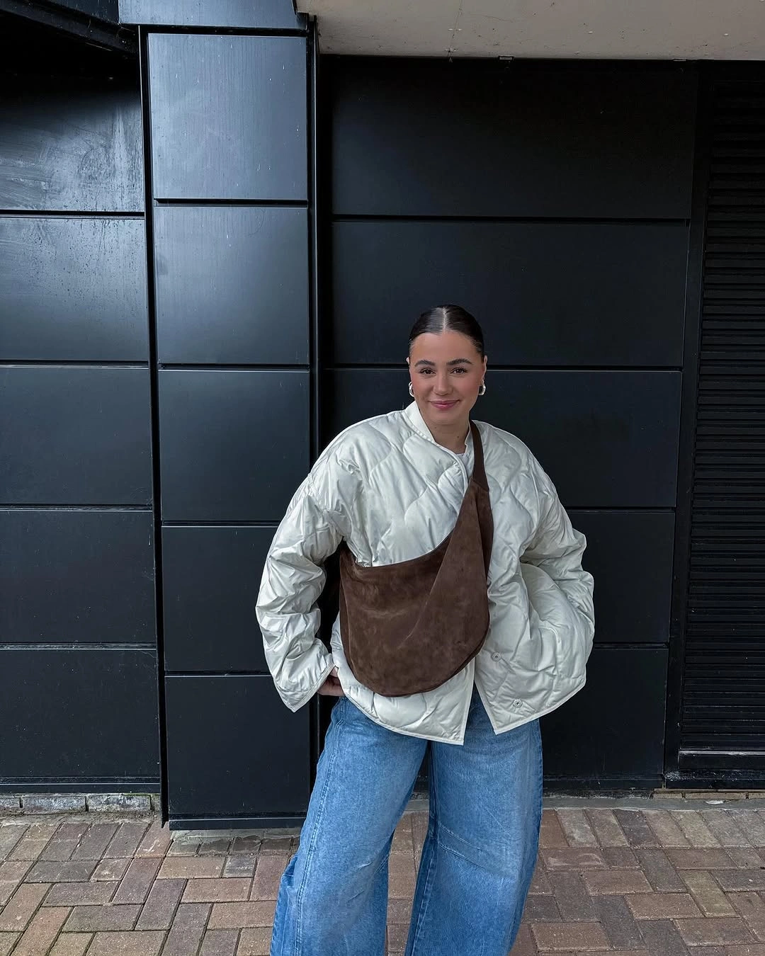 Pale quilted jacket with loose blue jeans and large brown crossbody bag