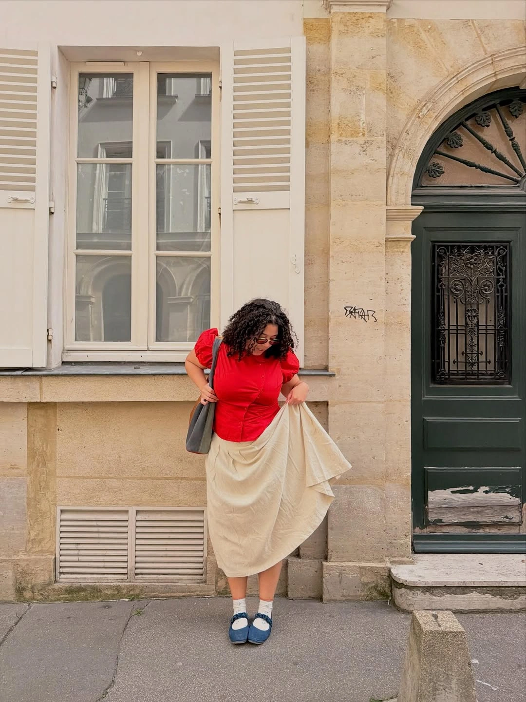Fitted red short-sleeved top cream midi skirt blue shoes and pale socks