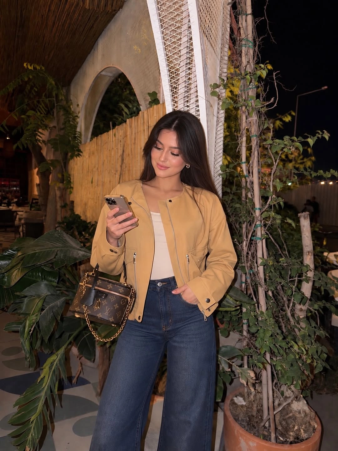 Tan cropped jacket over a pale top with dark blue wide-leg jeans