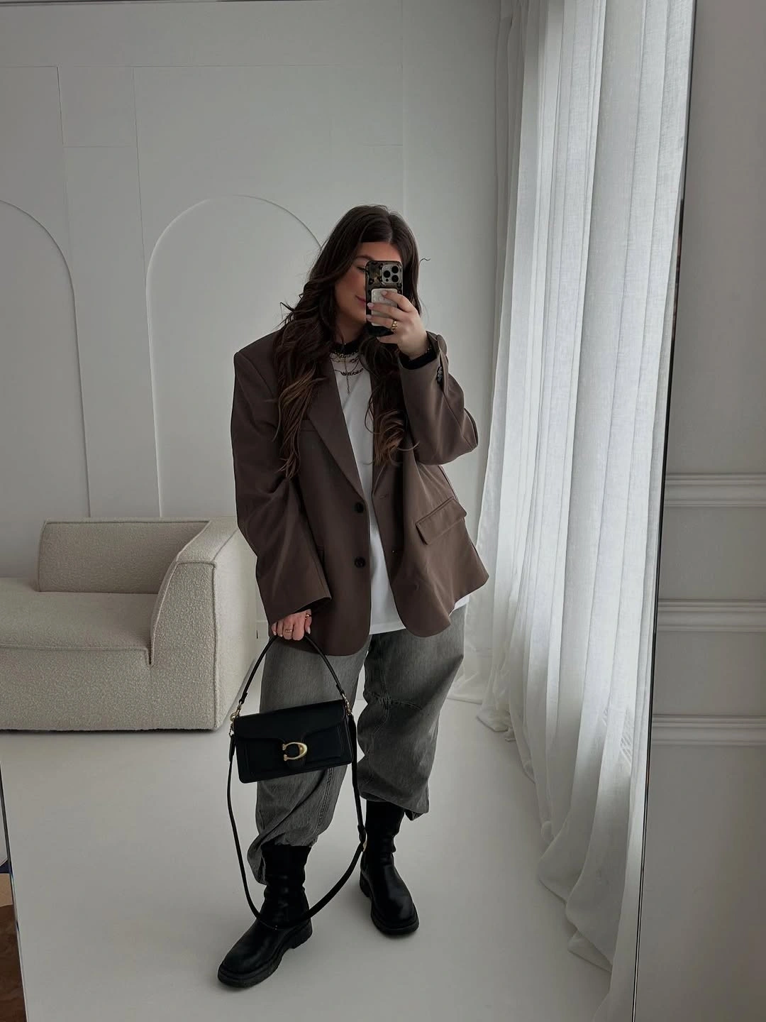 Oversized dark brown blazer with loose gray trousers black boots and handbag