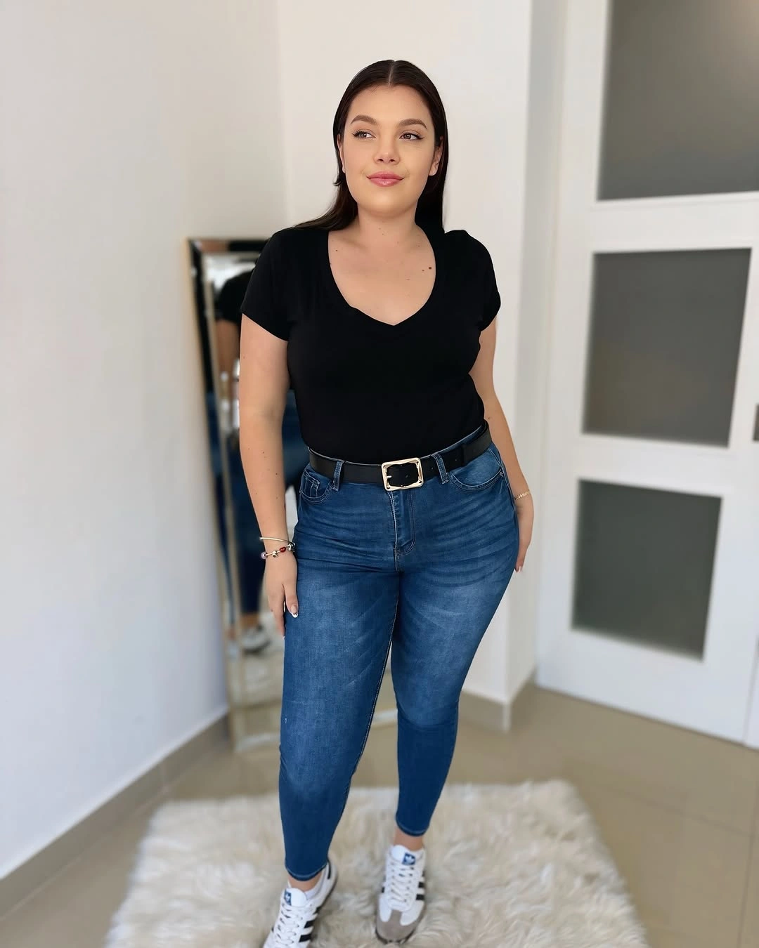 Black V-neck short-sleeved top blue fitted jeans belt and white sneakers