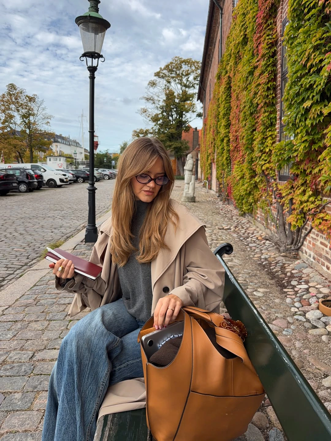 Beige trench charcoal top blue jeans and tan tote