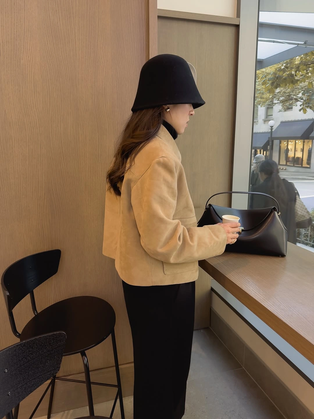 Camel jacket black trousers brimmed hat and handbag