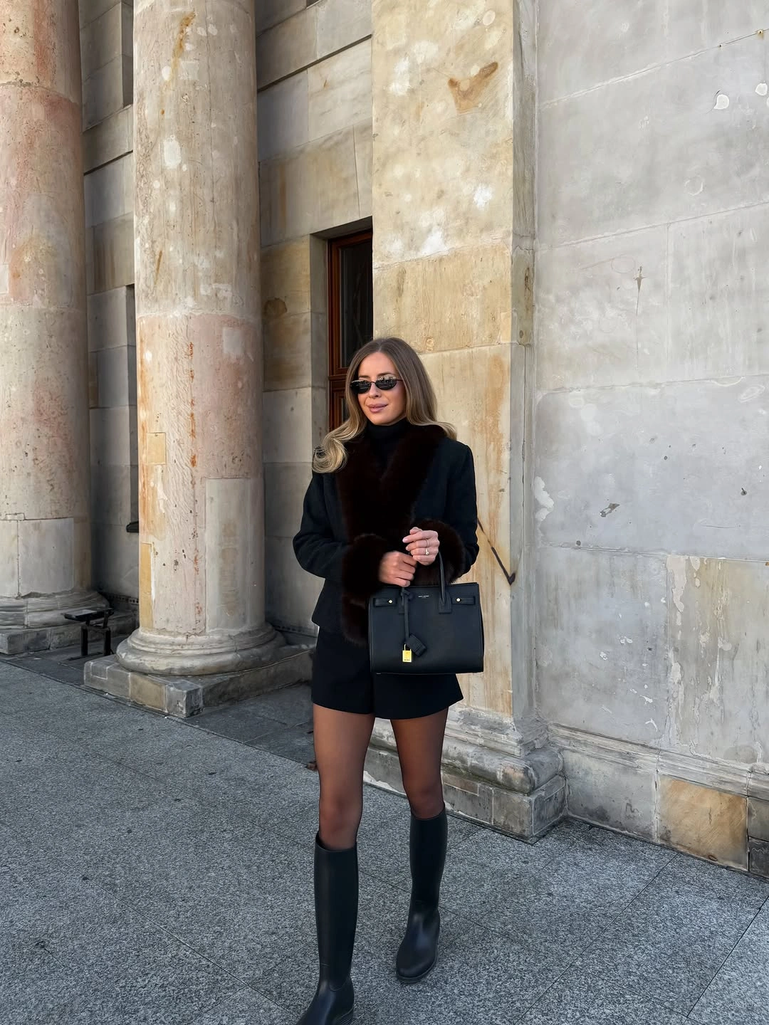 Black jacket shorts knee-high boots and structured handbag