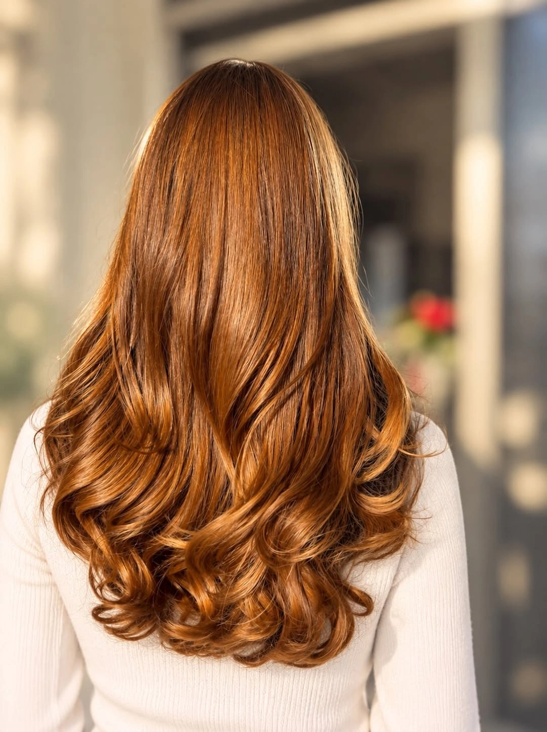 Long copper orange hair with warm amber reflections and curled ends