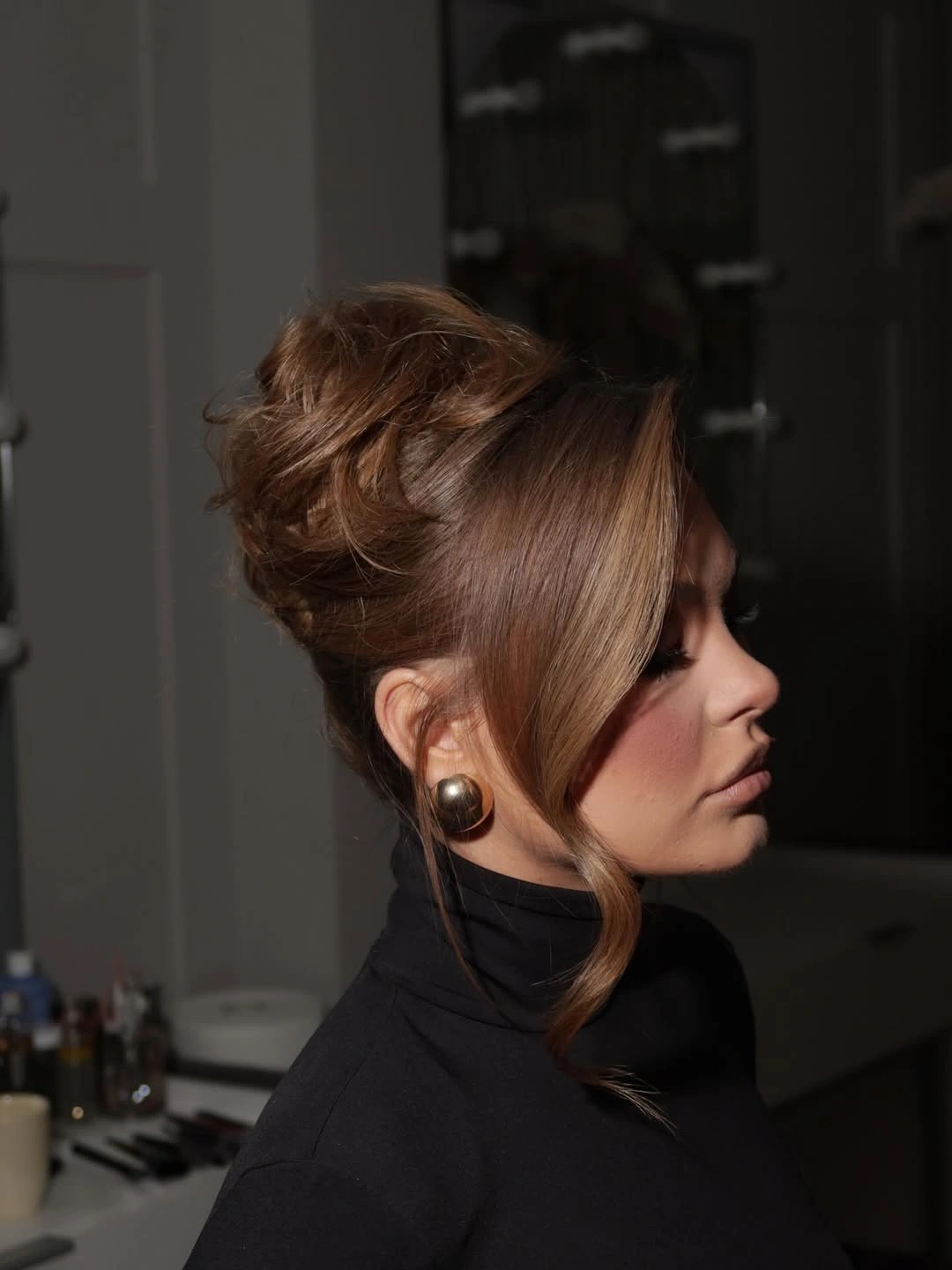 Warm auburn high textured updo with long loose face framing pieces