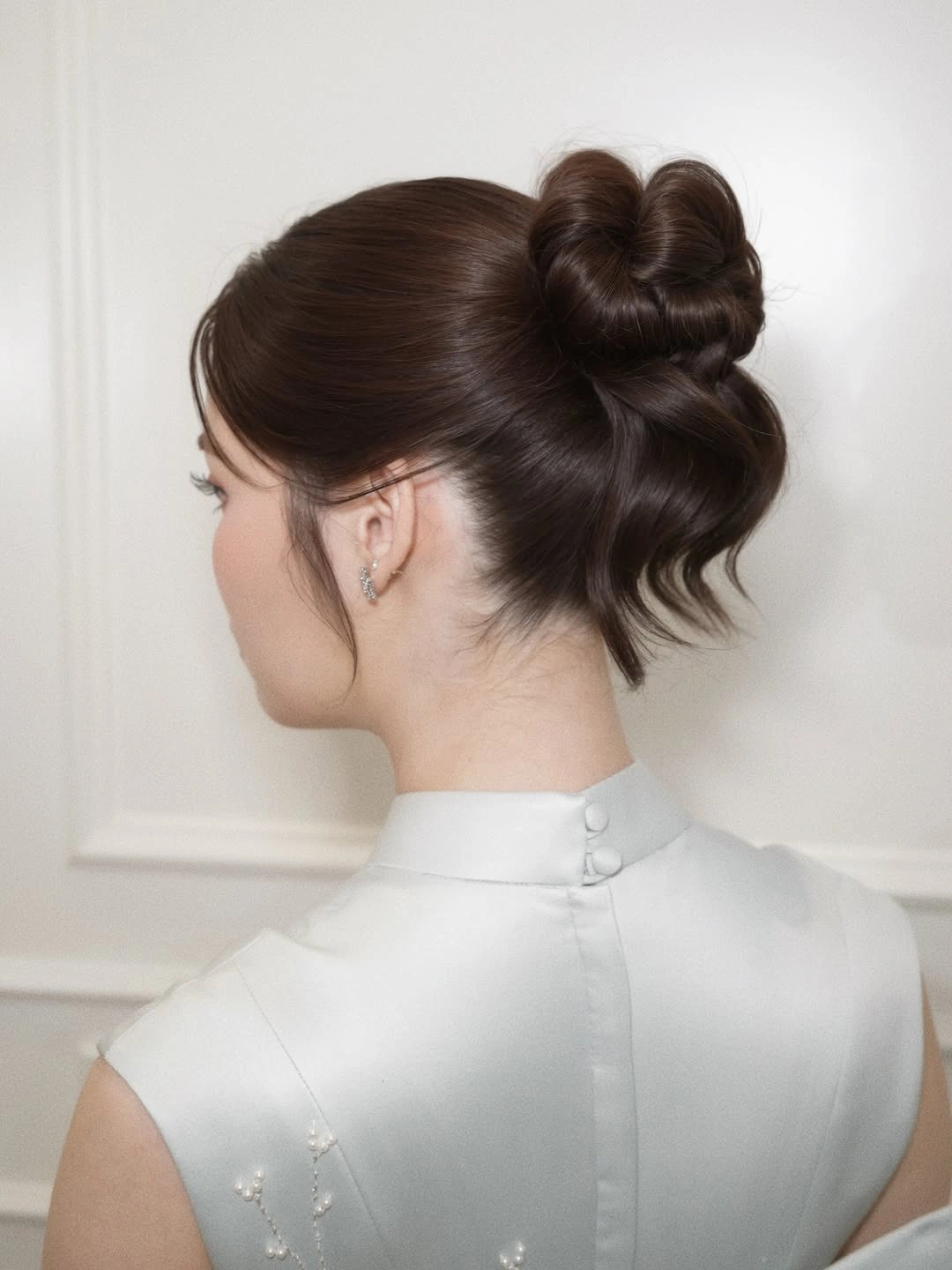 Dark brunette sculpted looped updo with smooth sides and loose ends