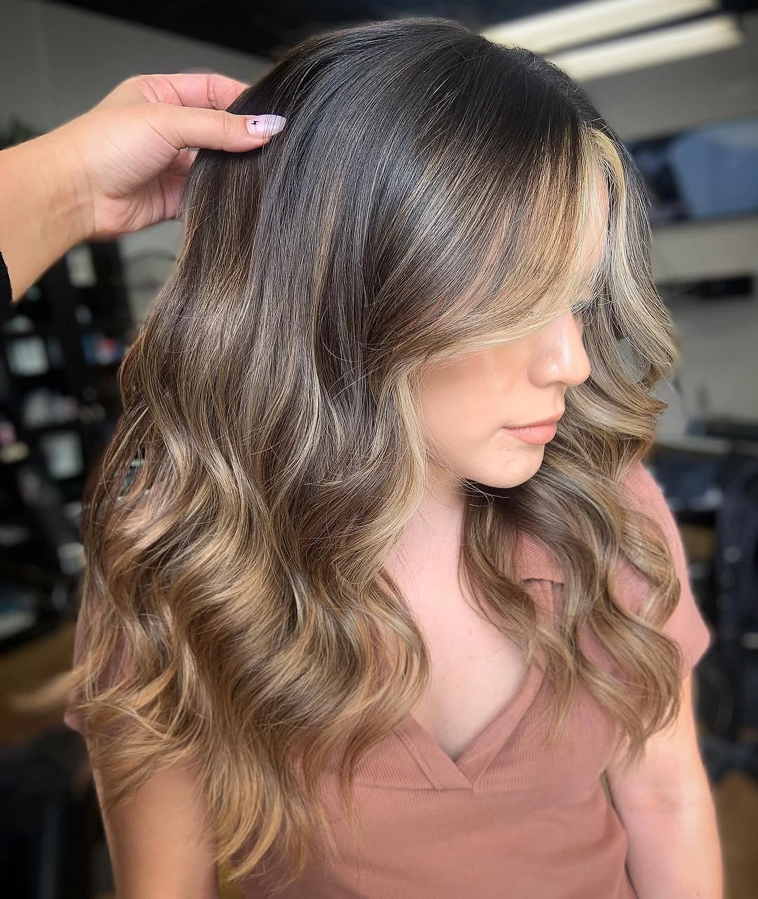 Long brunette waves with bright blonde face-framing sections and warm highlights