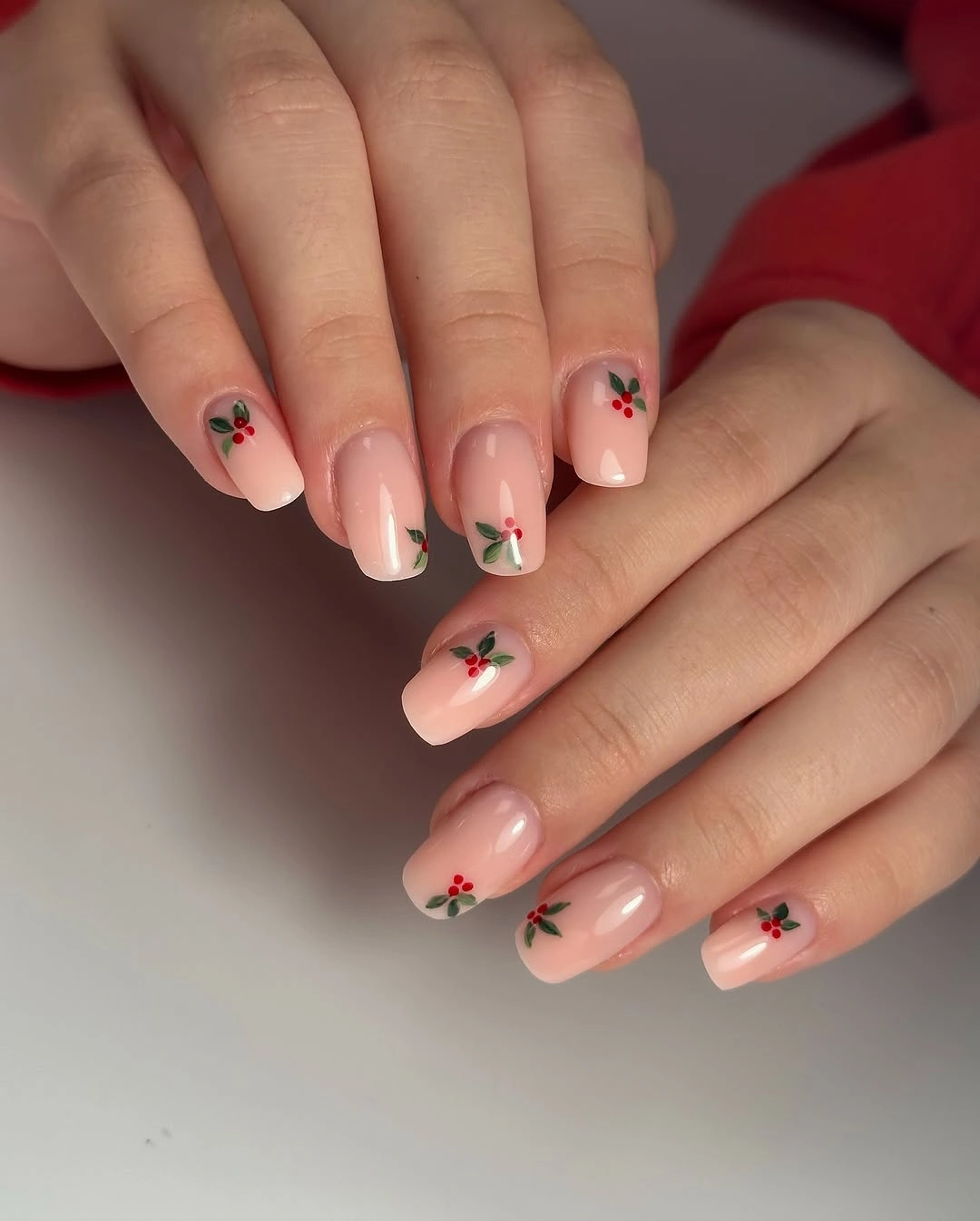 Glossy pale pink square nails with green leaves and red berries