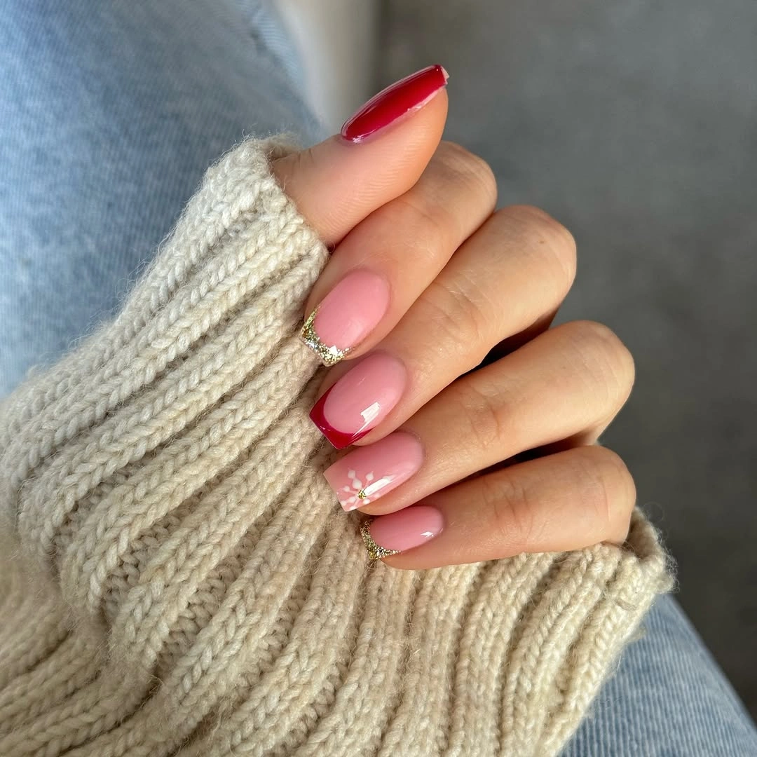 Glossy pink nails with red French tips, gold glitter, and white floral details