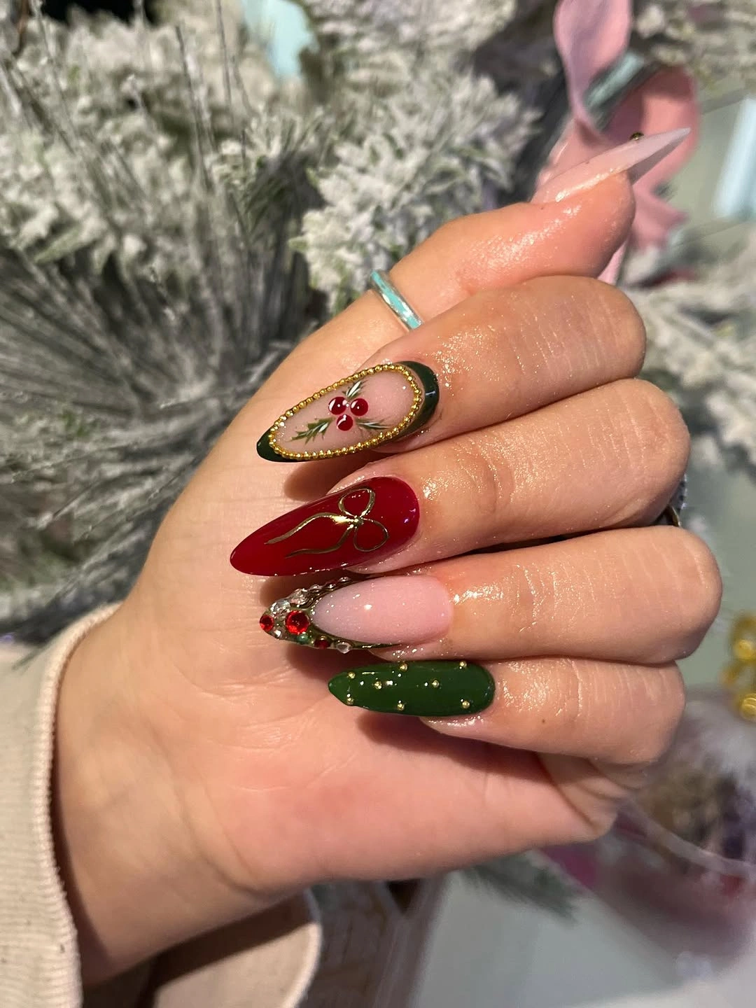 Long pointed nails with red green pink gold outlines and decorative gems
