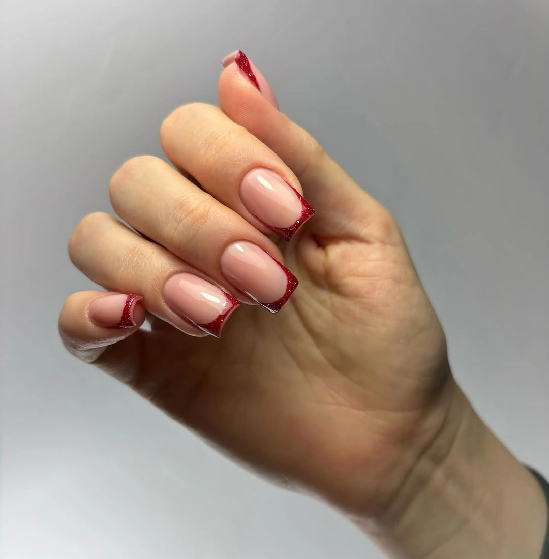 Glossy pink square nails with angled sparkling red French tips