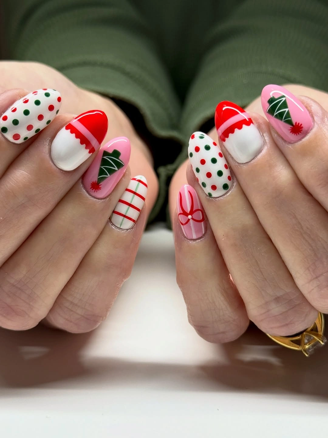 Short holiday nails with red stripes, green trees, polka dots, and bow