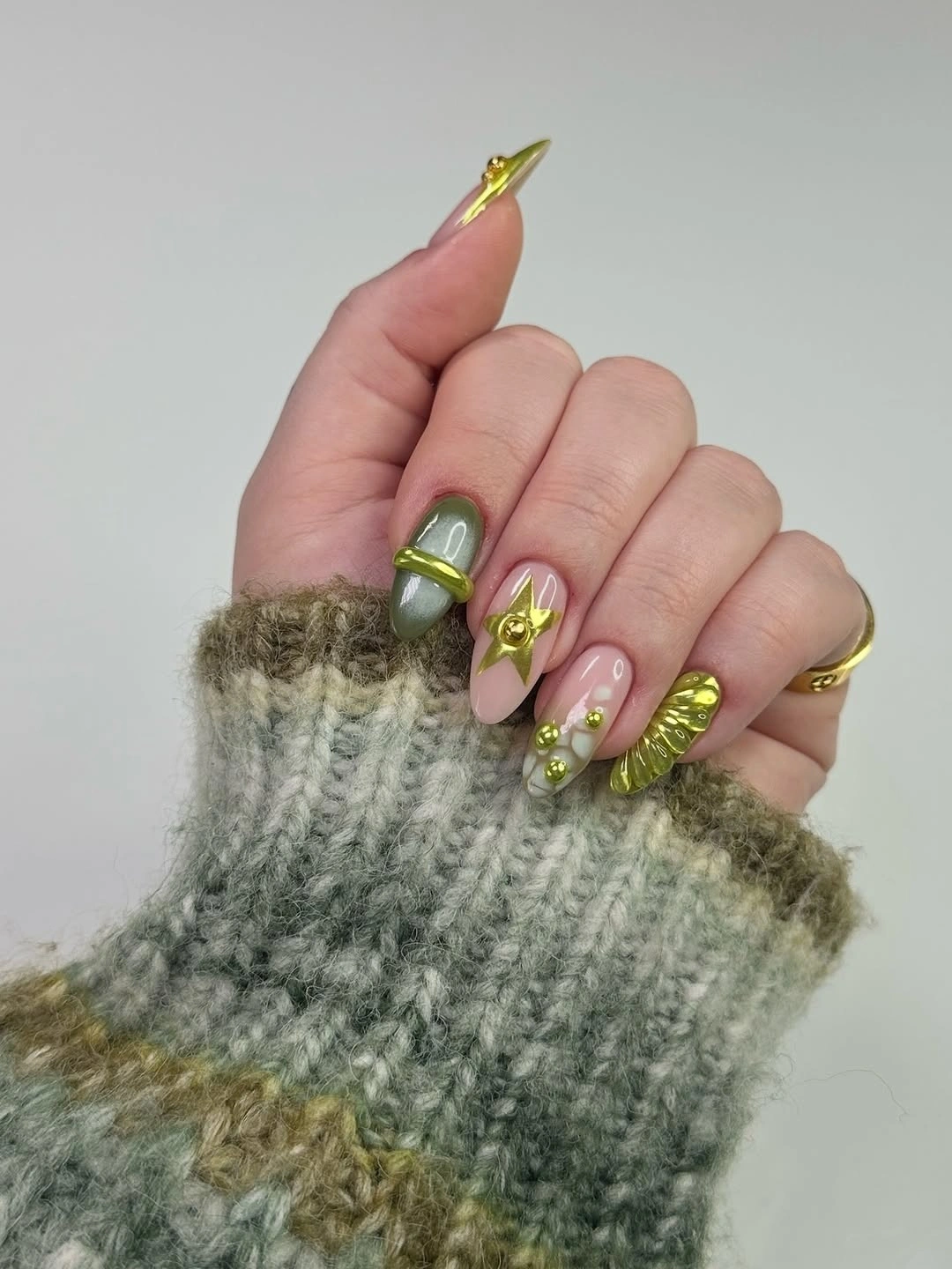 Sage green and pink nails with raised gold bands stars and beads