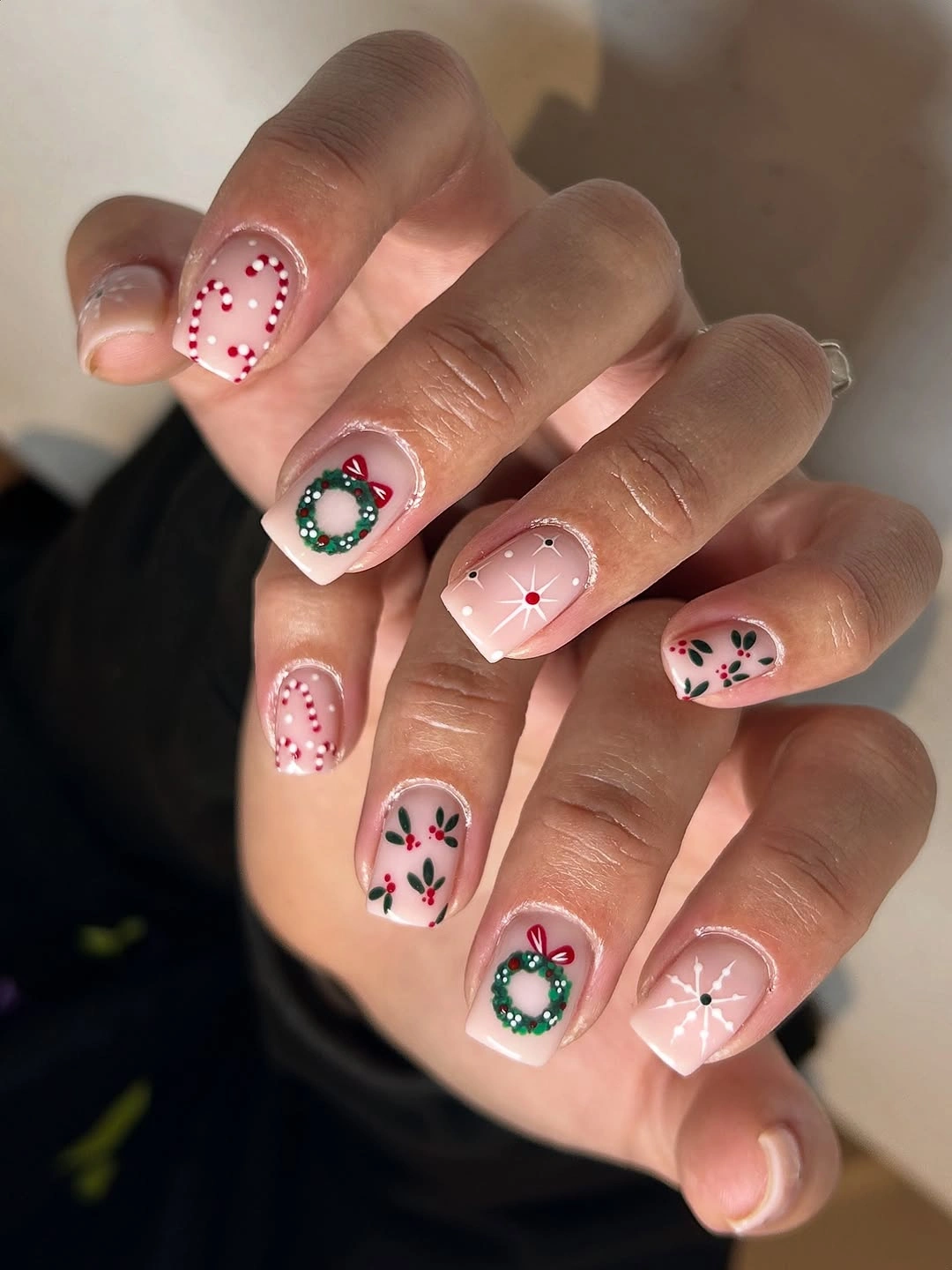 Blush pink square nails with wreaths, dotted candy canes, and starbursts