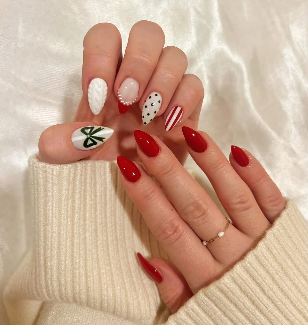 Red almond nails with white knit texture, green bow, dots, and stripes