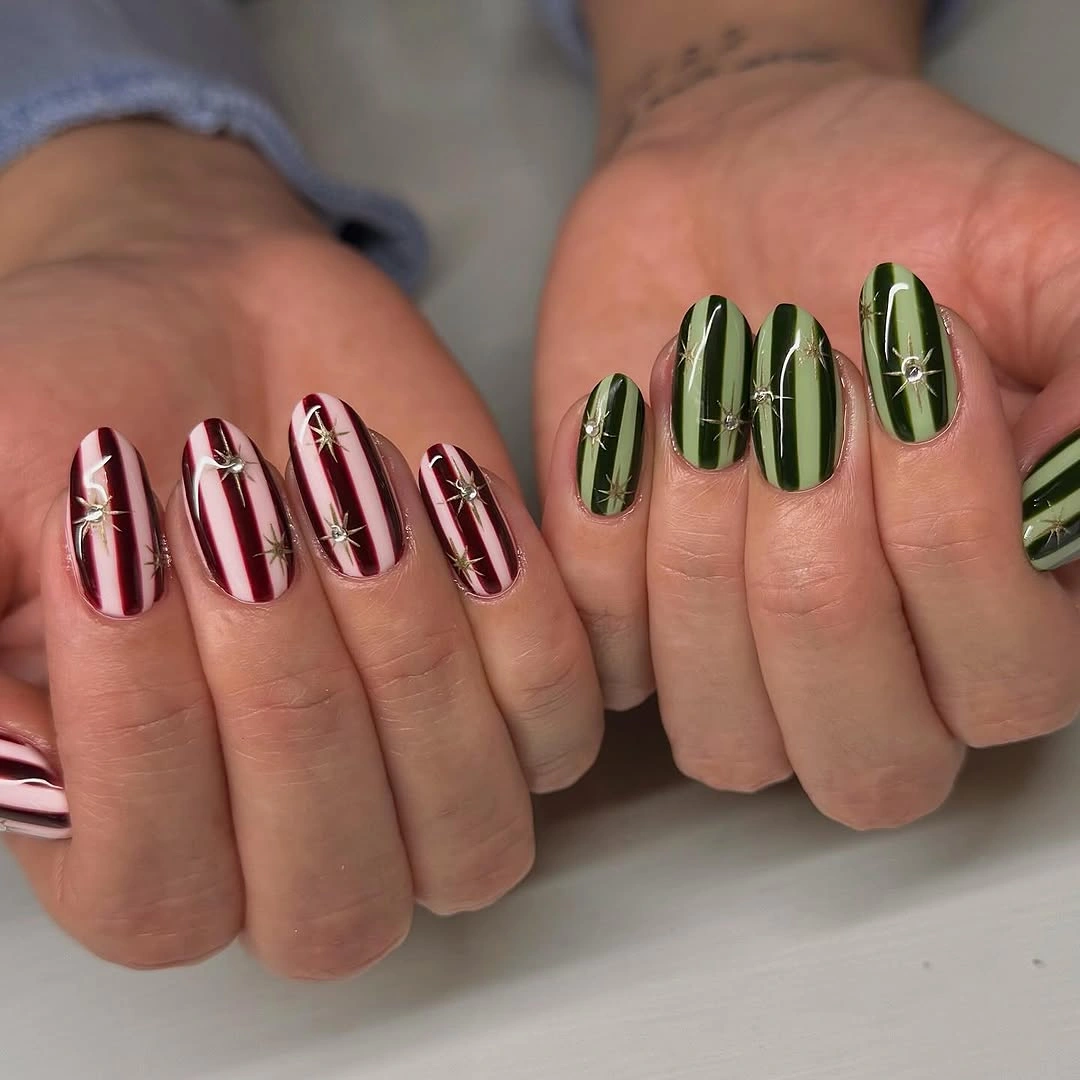 Oval nails with burgundy pink and olive green stripes and silver starbursts
