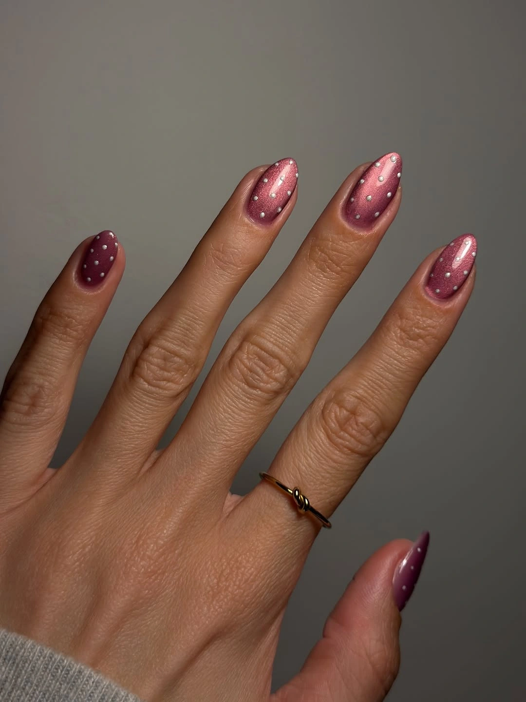 Mauve almond nails with luminous pink reflections and scattered white dots