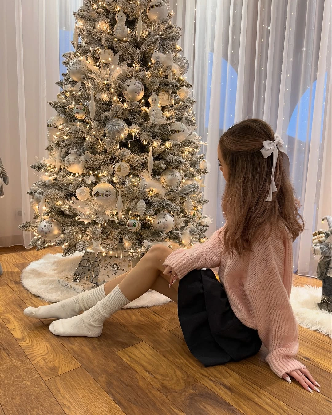 Blush pink sweater, short black lower garment, white socks and bow