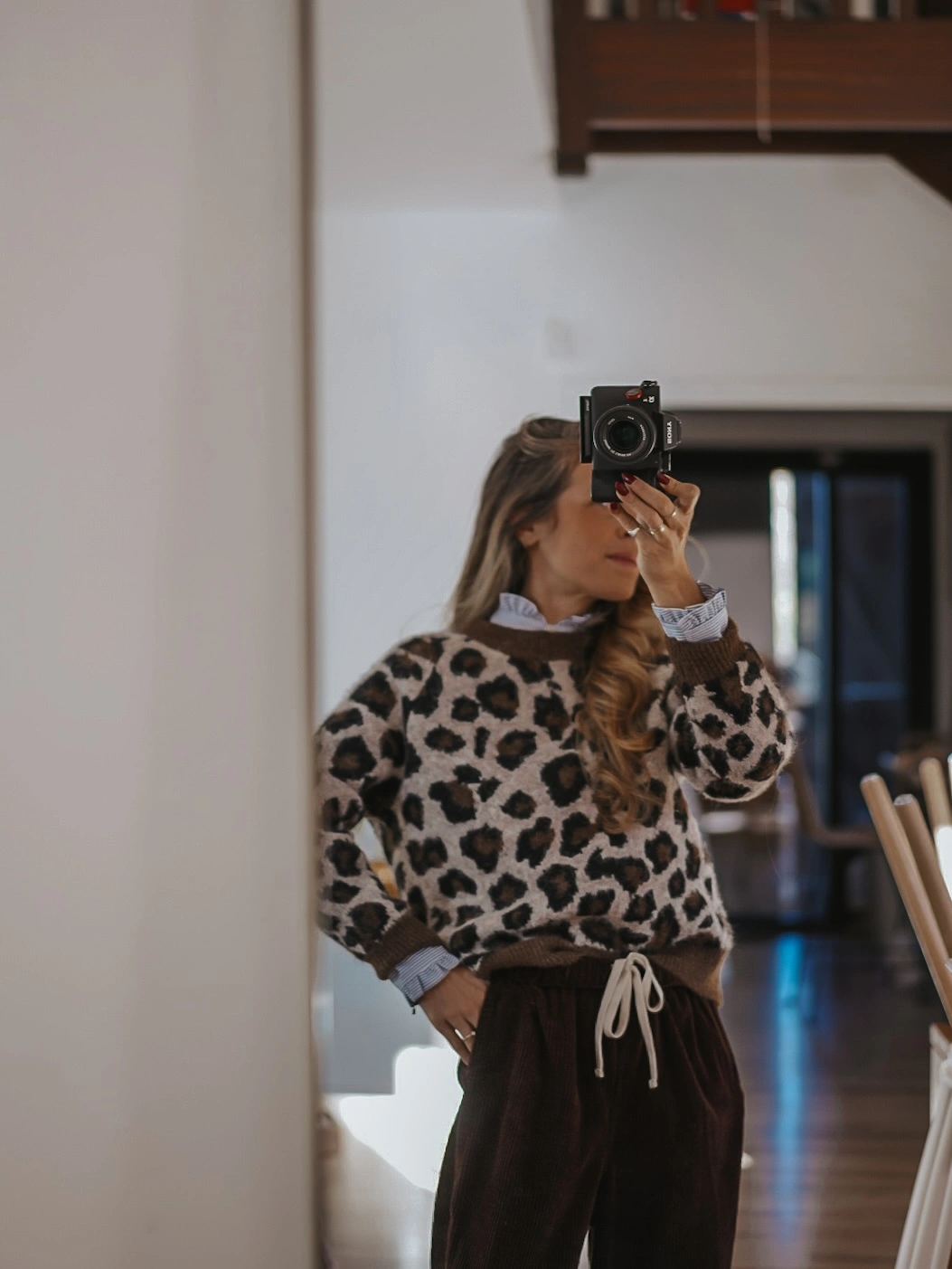 Leopard-pattern sweater over striped shirt with loose brown trousers