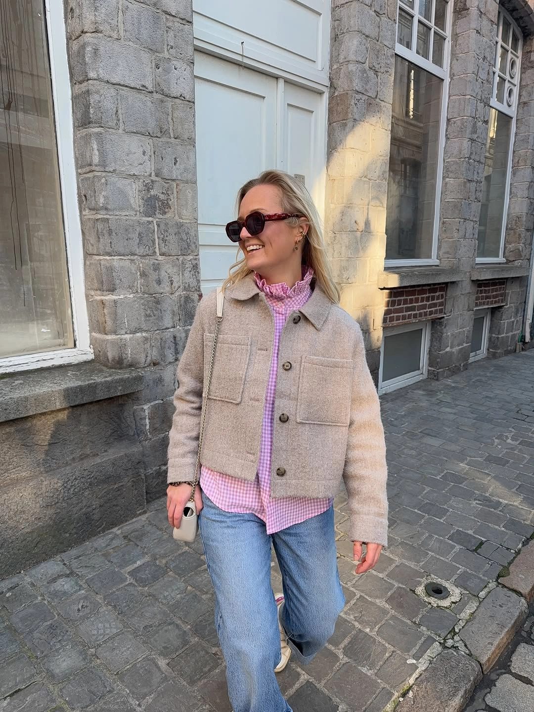 Beige button-front jacket over pink checked shirt and light blue jeans