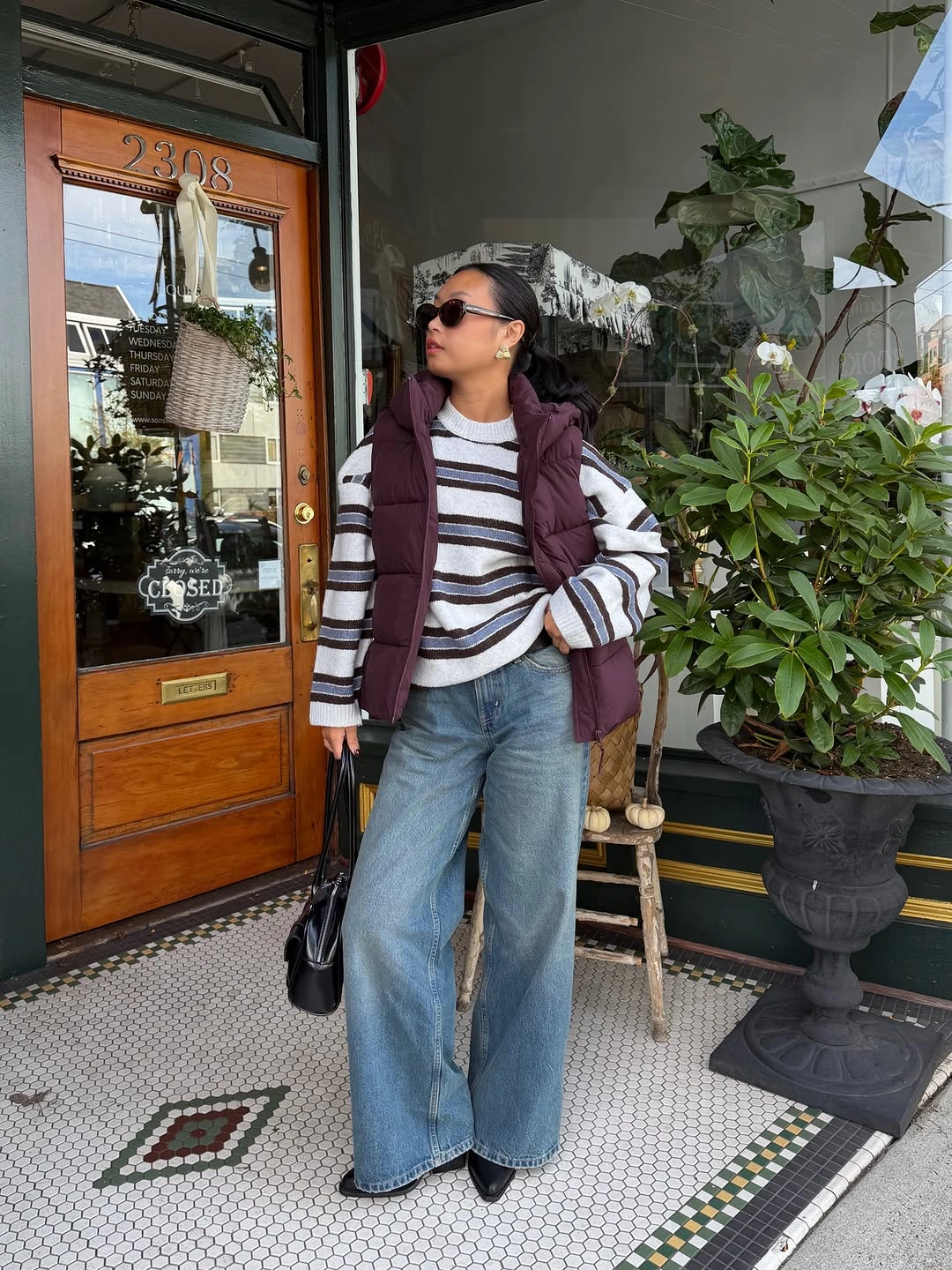 Burgundy padded vest with striped sweater and wide-leg jeans