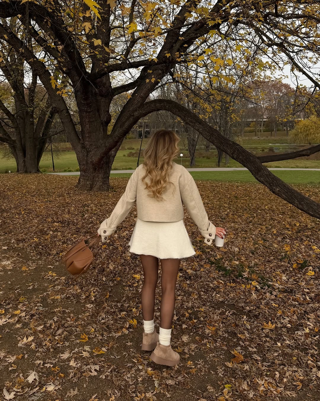 Cropped beige jacket with short pale lower piece and tan shoes