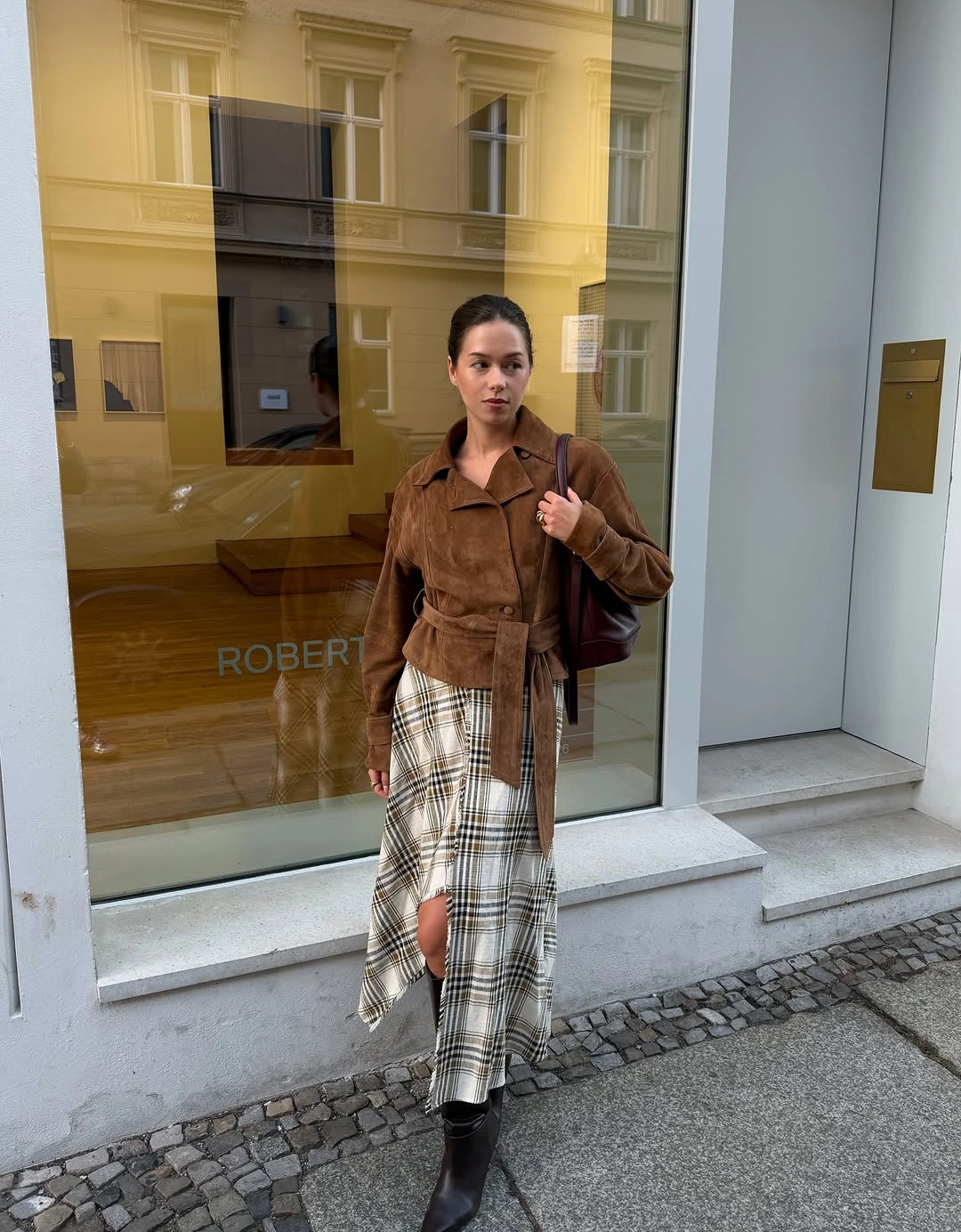 Brown belted jacket with asymmetric plaid skirt and black boots