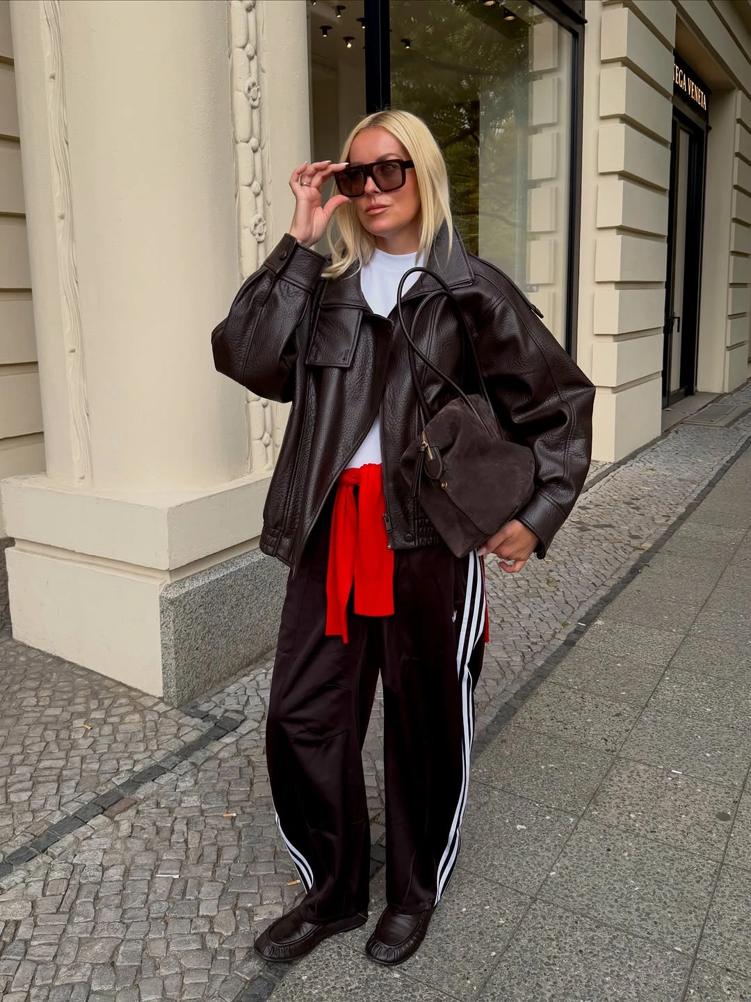 Oversized brown leather jacket with striped black track pants
