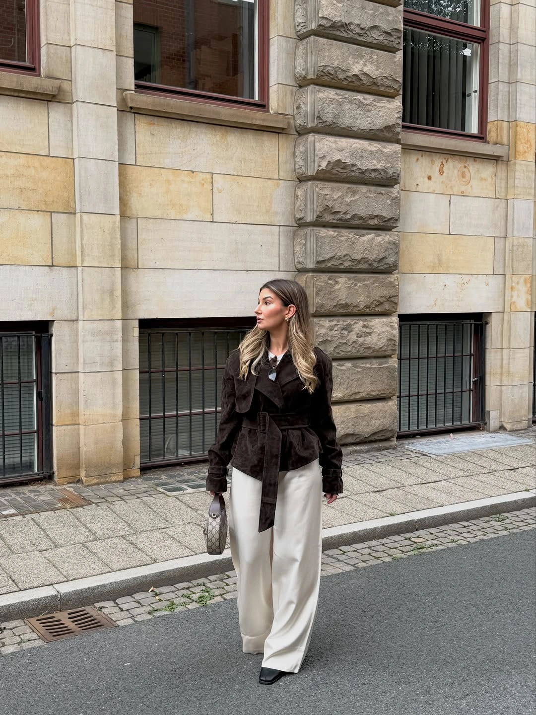 Black belted jacket with wide white trousers and pointed shoes