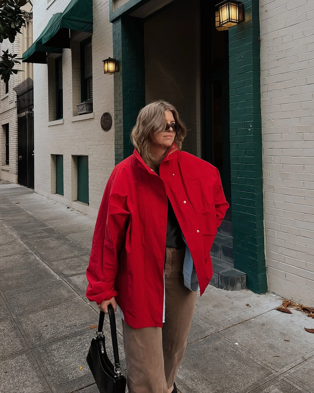 Oversized red jacket with brown trousers and black handbag