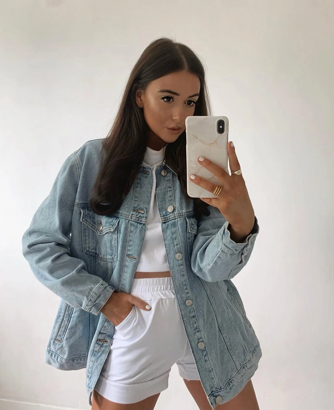 Light-wash denim jacket over white cropped top and shorts