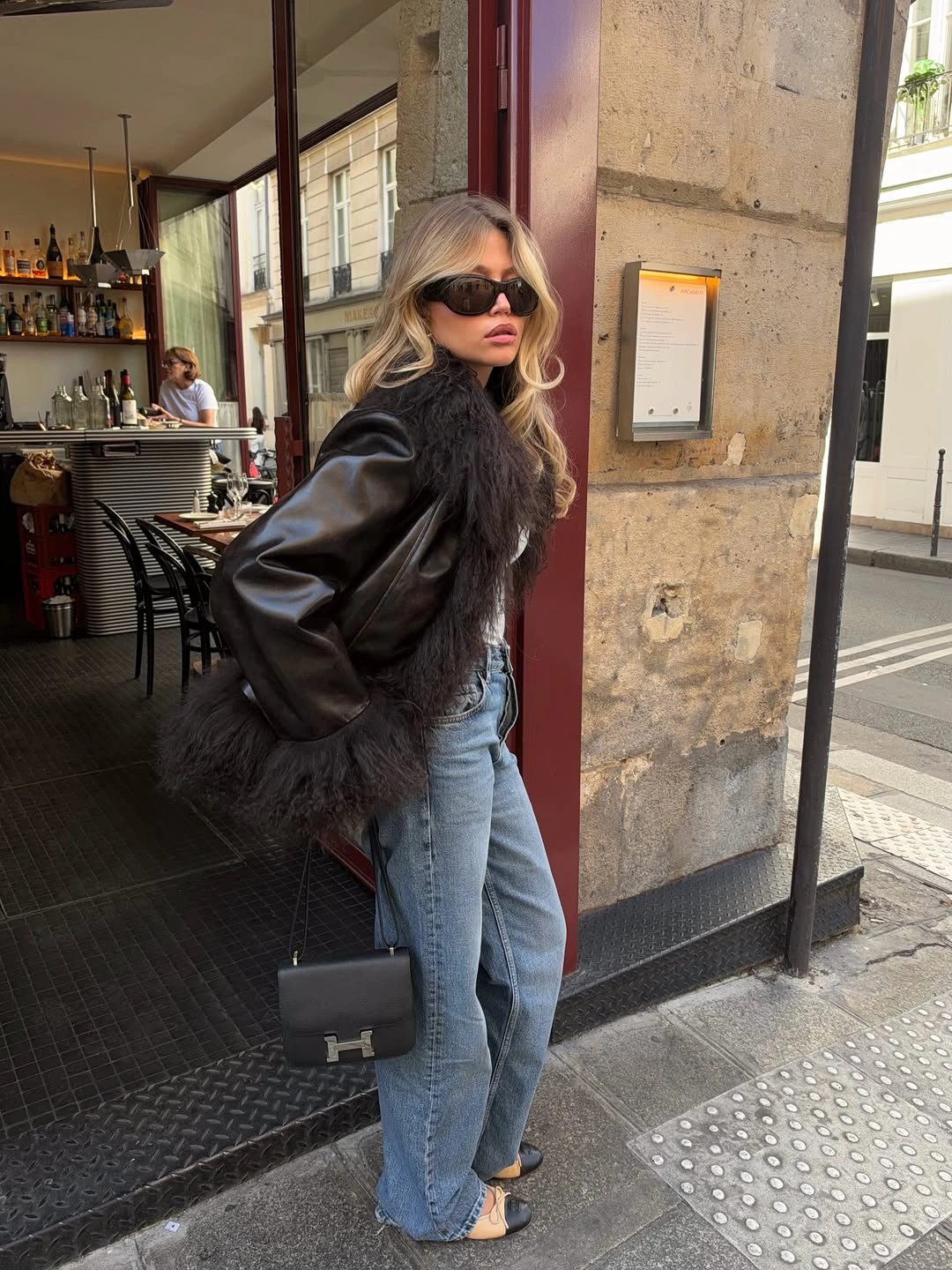 Textured black outerwear with light wide-leg jeans and black bag