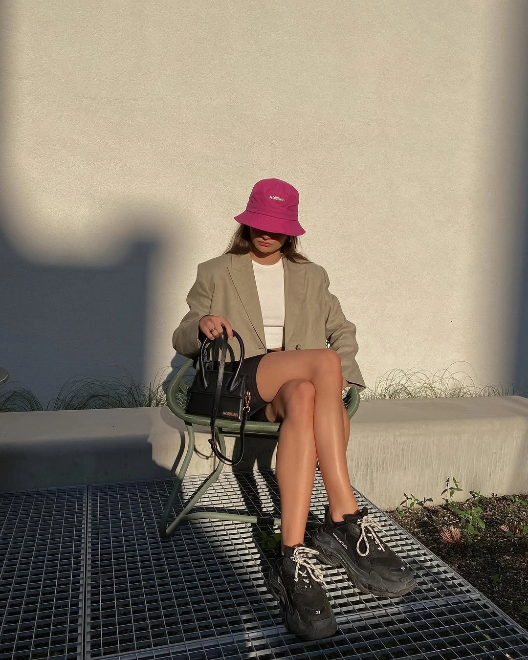 Beige blazer with pink bucket hat, dark sneakers, and black handbag
