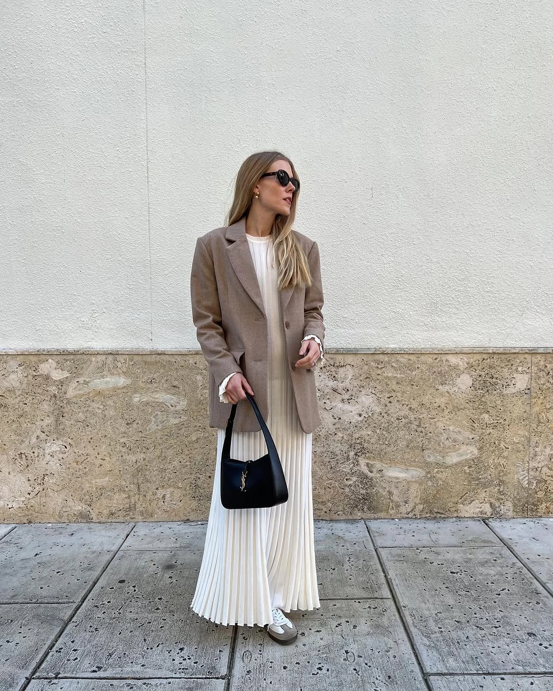 Taupe oversized blazer over long white pleated dress with black shoulder bag