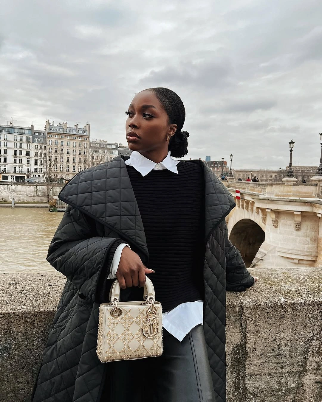 Black quilted outer layer over dark sweater and white collared shirt