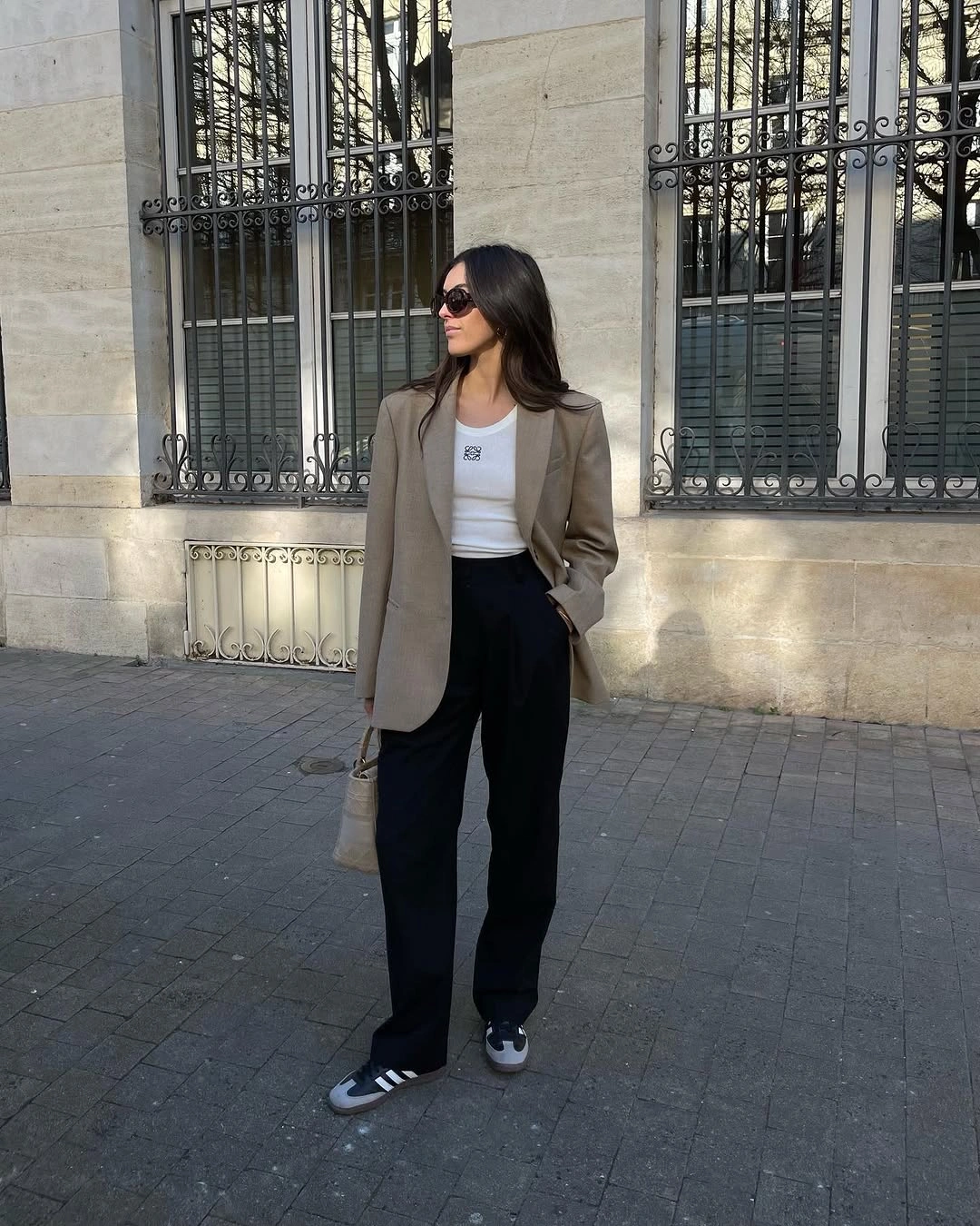 Oversized taupe blazer with white top, black trousers, and striped sneakers
