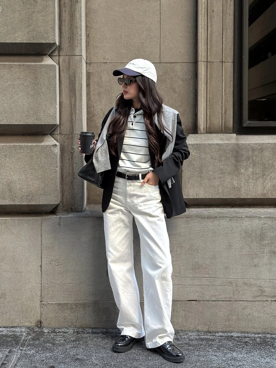 White baseball cap with dark blazer, striped top, cream trousers, and loafers