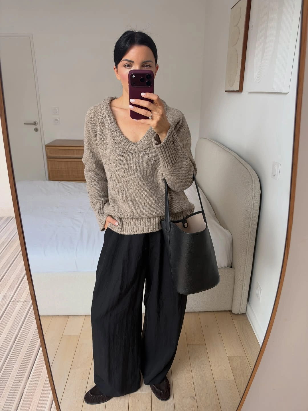 Taupe V-neck sweater with wide black trousers and large shoulder bag