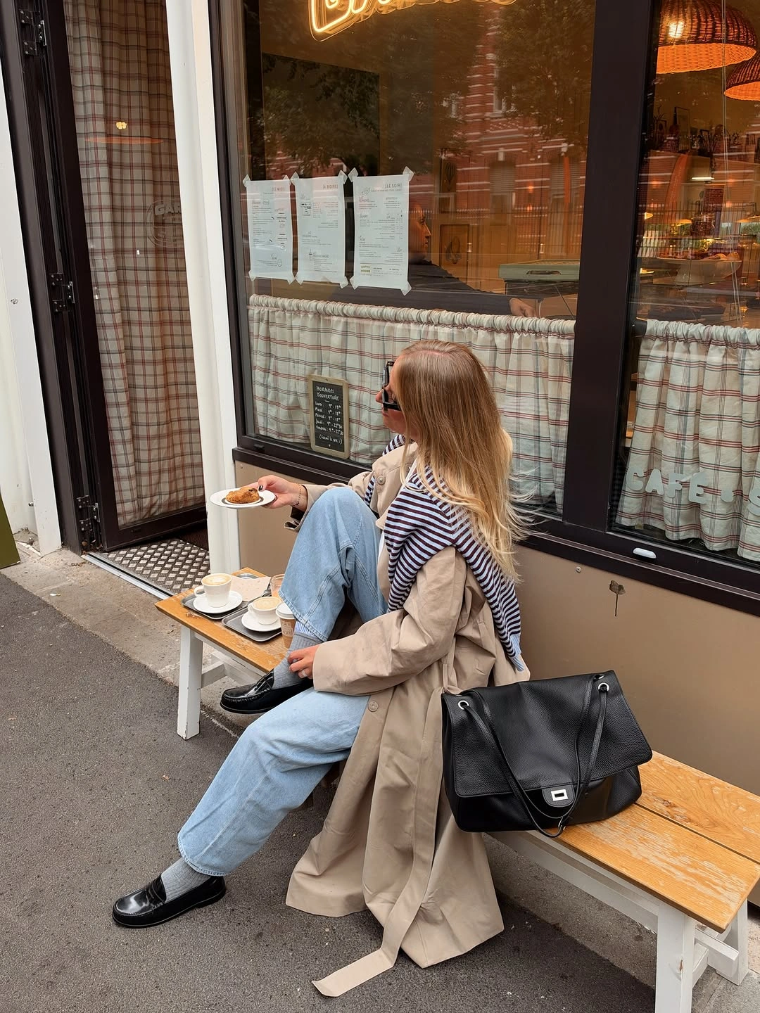 Beige trench coat with striped shoulder layer, blue jeans, and black loafers