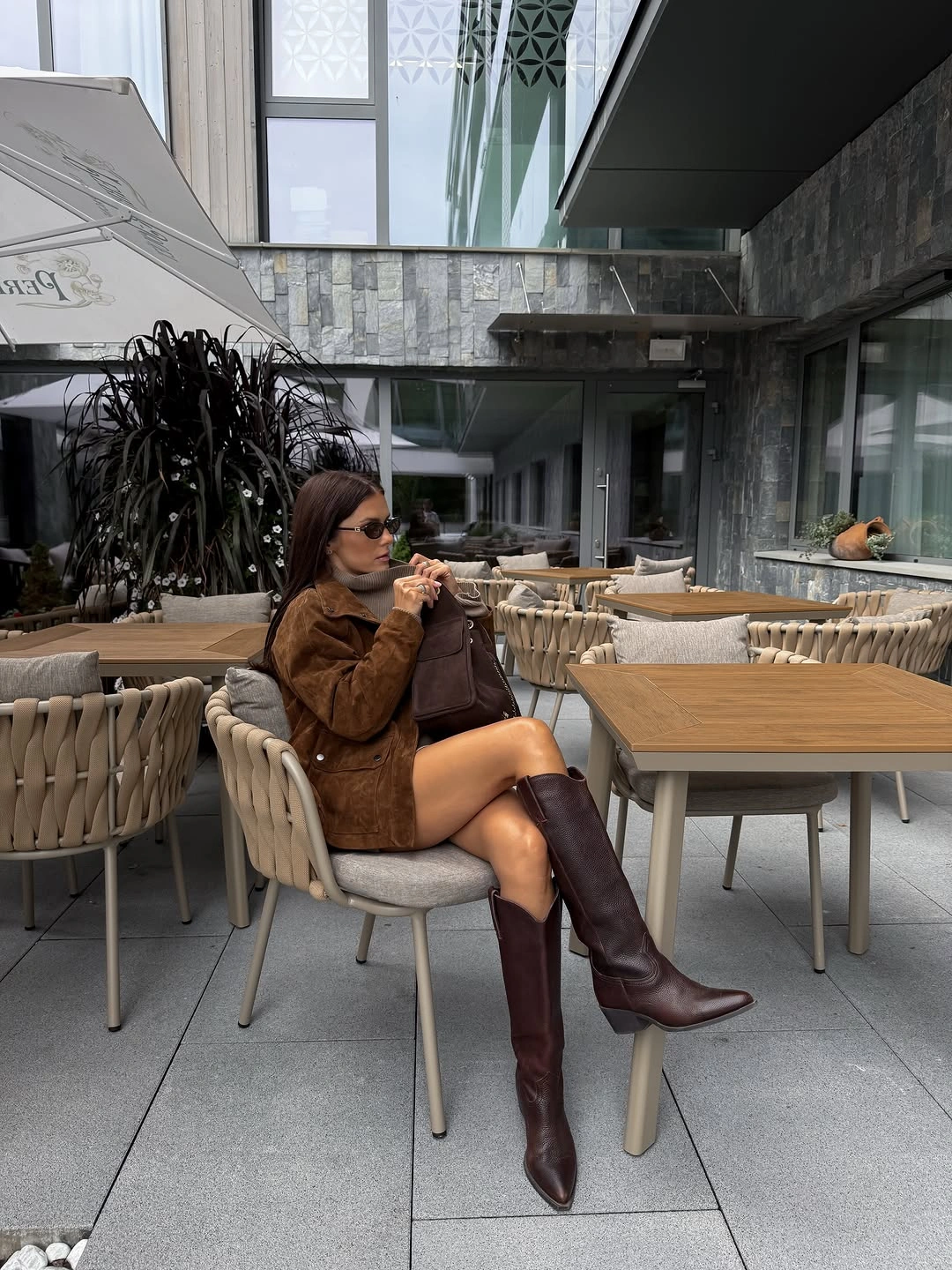 Textured brown jacket, gray high-neck top, dark handbag, and tall brown boots